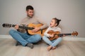 Dad plays the guitar with his daughter. The child learns to play a musical instrument with a tutor. Musical duet of a Royalty Free Stock Photo