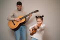 Dad plays the guitar with his daughter. The child learns to play a musical instrument with a tutor. Musical duet of a Royalty Free Stock Photo