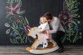 Dad plays with his daughter. Father rolls a little daughter on a toy horse. Royalty Free Stock Photo