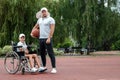 Dad plays with his disabled son on the sports ground. Concept wheelchair, disabled person, fulfilling life, father and son,