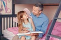 Dad reading book to little daughter girl. Happy family of two sitting on a bed in bedroom. Smiling father and child at home Royalty Free Stock Photo