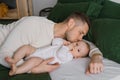 Dad`s kiss of his six-month-old son lying on the bed at home Royalty Free Stock Photo