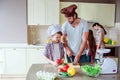 Dad shows his son how to cut vegetables right. Gir works with her mom behind boy close to stowe. Family is preparing Royalty Free Stock Photo