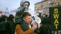 Dad, single parent, protesting with bullhorn. Boy sits on fathers shoulders.