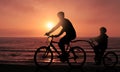 Dad and Son Biking Together At Sunrise Time on the Beach Royalty Free Stock Photo