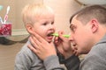 Dad and son brush their teeth in the bathroom. Father Brushing Teeth to Child