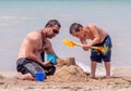 Dad and son building castles on the beach Royalty Free Stock Photo