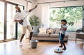 Dad and son having fun while cleaning at home. African american father and boy playing air guitar with mop and broom Royalty Free Stock Photo