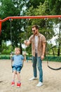 dad and son having fun on swing at playground Royalty Free Stock Photo