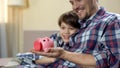 Dad and son holding piggy-bank and smiling, social welfare, health insurance Royalty Free Stock Photo