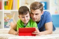 Dad and son kid play with tablet computer indoors Royalty Free Stock Photo