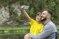 Dad and son make smartphone photography on nature in summer day