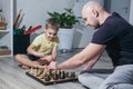 Dad and son play chess on the floor in the children`s room among the toys Royalty Free Stock Photo