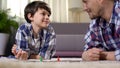 Dad and son playing board game, developing logical thinking skills, fatherhood