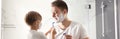 Dad and son with shaving foam on their faces having fun in bathroom. Banner design Royalty Free Stock Photo