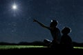 Dad and son sit on the grass at night and look at the night sky Royalty Free Stock Photo