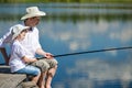 Dad and son are sitting on the pier and fishing on the river Royalty Free Stock Photo