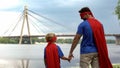 Dad and son in superhero costumes holding hands, father protection and support