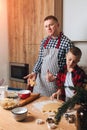 Dad and son at a wooden table in the kitchen are making cookies in the shape of little human