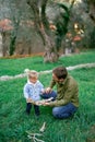 Dad squatted down near a little girl in the park showing a tangled tree branch in his palm Royalty Free Stock Photo