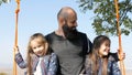 Portrait of dad swinging with daughters on a swing under a tree. Royalty Free Stock Photo