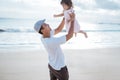 Dad swinging his toddler daughter into the air on the beach having fun together Royalty Free Stock Photo