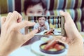 Dad take mobile photo of Asian boy eating French fries Royalty Free Stock Photo