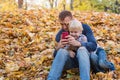 Dad teaches child to take pictures on phone. Father and son sitting in autumn Park