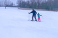 Dad teaches daughter to ski. A skier holds a little girl by the hand and helps to ski. An instructor teaches a child winter sports Royalty Free Stock Photo