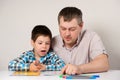 Dad teaches his son to read, names and write letters together. Parent prepares child for school.