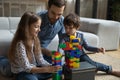 Dad teaching son and daughter to build tower from blocks