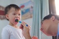 Dad teaching son teeth brushing, Cute little Asian 2 - 3 years old toddler boy child learn to brushing teeth in the morning in