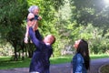 Dad throws his daughter in air and catches in city park, mom stands near family. Royalty Free Stock Photo