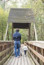 Dad and toddler daughter walking on a wooden bridge in a park. Royalty Free Stock Photo