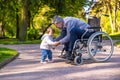 Dad on wheelchair playing with his little son in the park Royalty Free Stock Photo