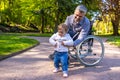 Dad on wheelchair playing with his little son in the park Royalty Free Stock Photo