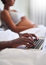 Daddies to be should be just as informed as mommies. Defocused shot of a man using his laptop while sitting in bed with