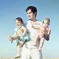 Daddy carrying children on his hands. Father and two daughters playing against blue sky