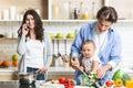 Daddy cooking salad with baby son, mother talking on phone