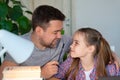 Daddy helps daughter with online lessons on laptop