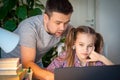 Daddy helps girl with online lessons on laptop