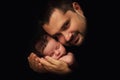 Daddy hugs his newborn baby. Father's love. Close-up portrait on a black background Royalty Free Stock Photo