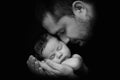 Daddy hugs his newborn baby. Father `s love. Close-up portrait on a black background Royalty Free Stock Photo