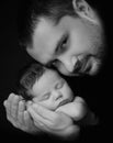 Daddy hugs his newborn baby. Father `s love. Close-up portrait on a black background Royalty Free Stock Photo