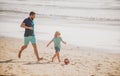 Daddy with kid boy playing on a summer day. Father and son play soccer or football on the beach. Lifestyle and family Royalty Free Stock Photo