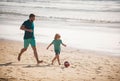 Daddy with kid boy playing on a summer day. Father and son play soccer or football on the beach. Lifestyle and family Royalty Free Stock Photo