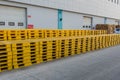 Plastic yellow pallets stacked neatly behind warehouse