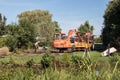 Daewoo industrial digger on work site. Male worker working on dug area of land.