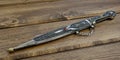 Dagger with ornate pattern on wooden background