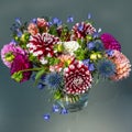 Dahlia flower bouquet with blue thistles and African lilies in vibrant colors, summer flowers in arrangement.